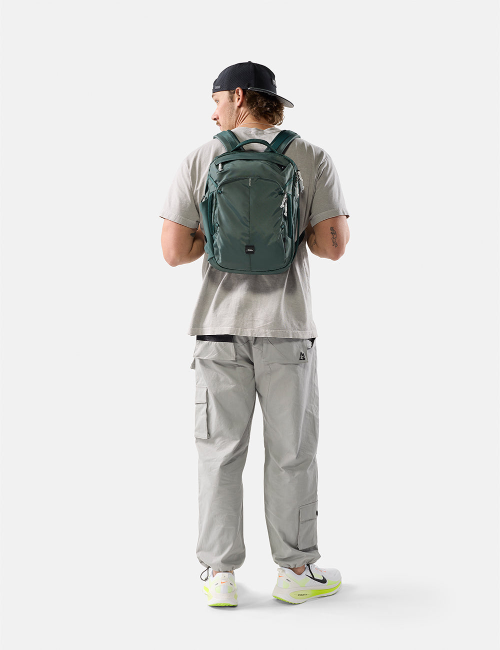 Person wearing a green backpack on a white background