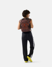 Person wearing a garnet backpack with orange accents on a white background