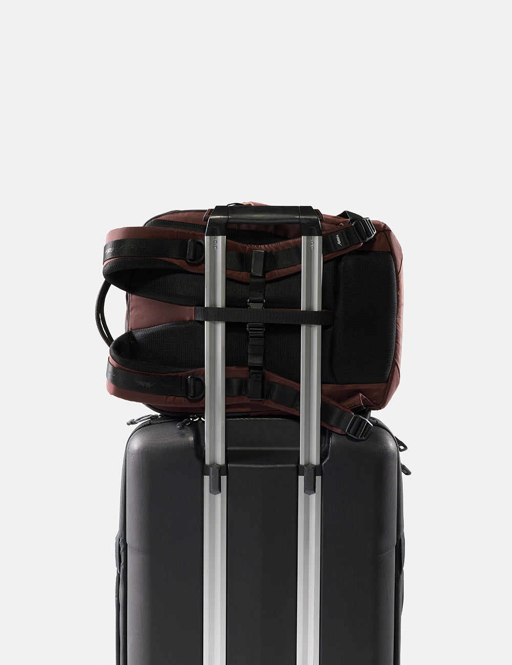 Backpack attached to a suitcase on a light gray background