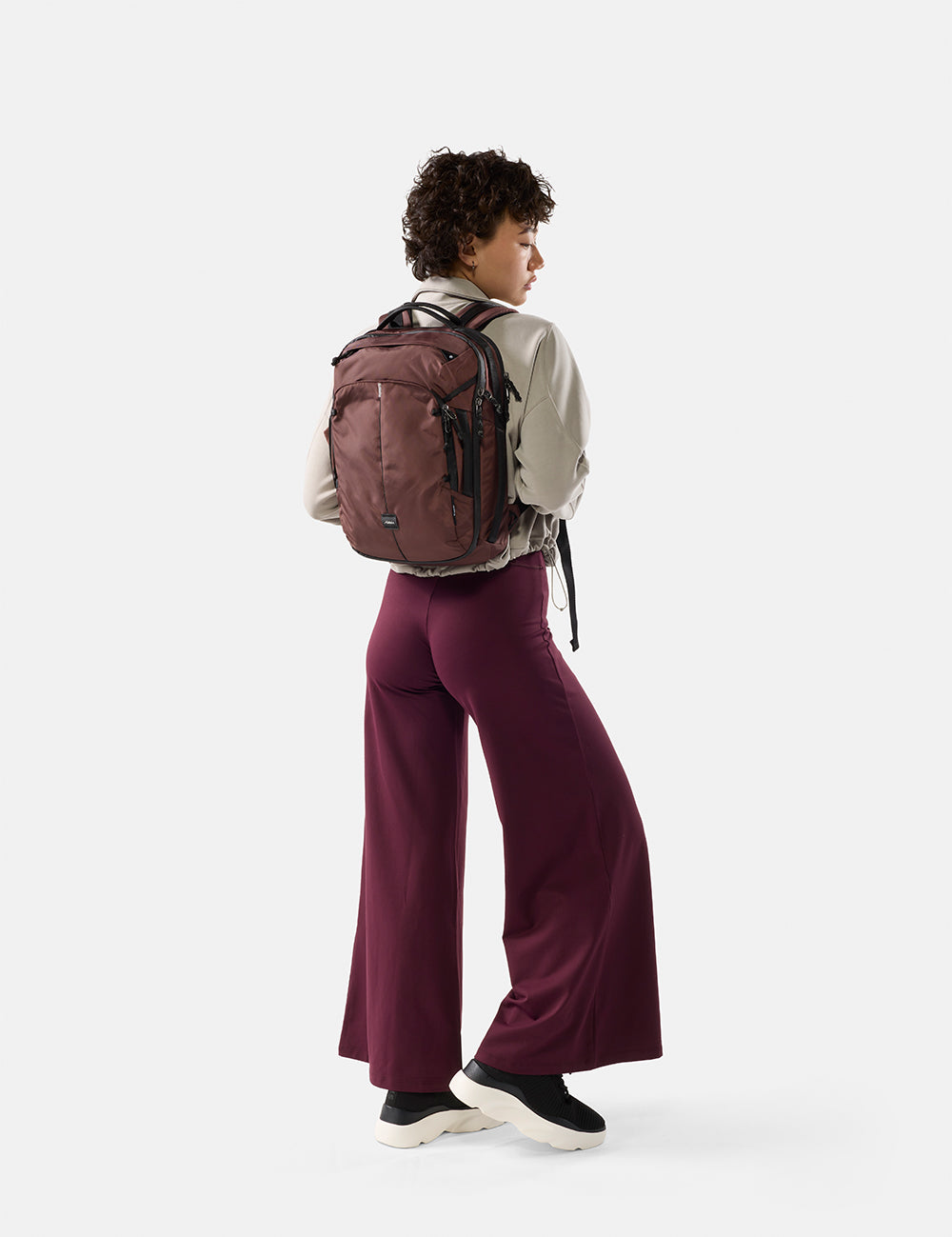 Person wearing a garnet  backpack and garnet  pants on a white background