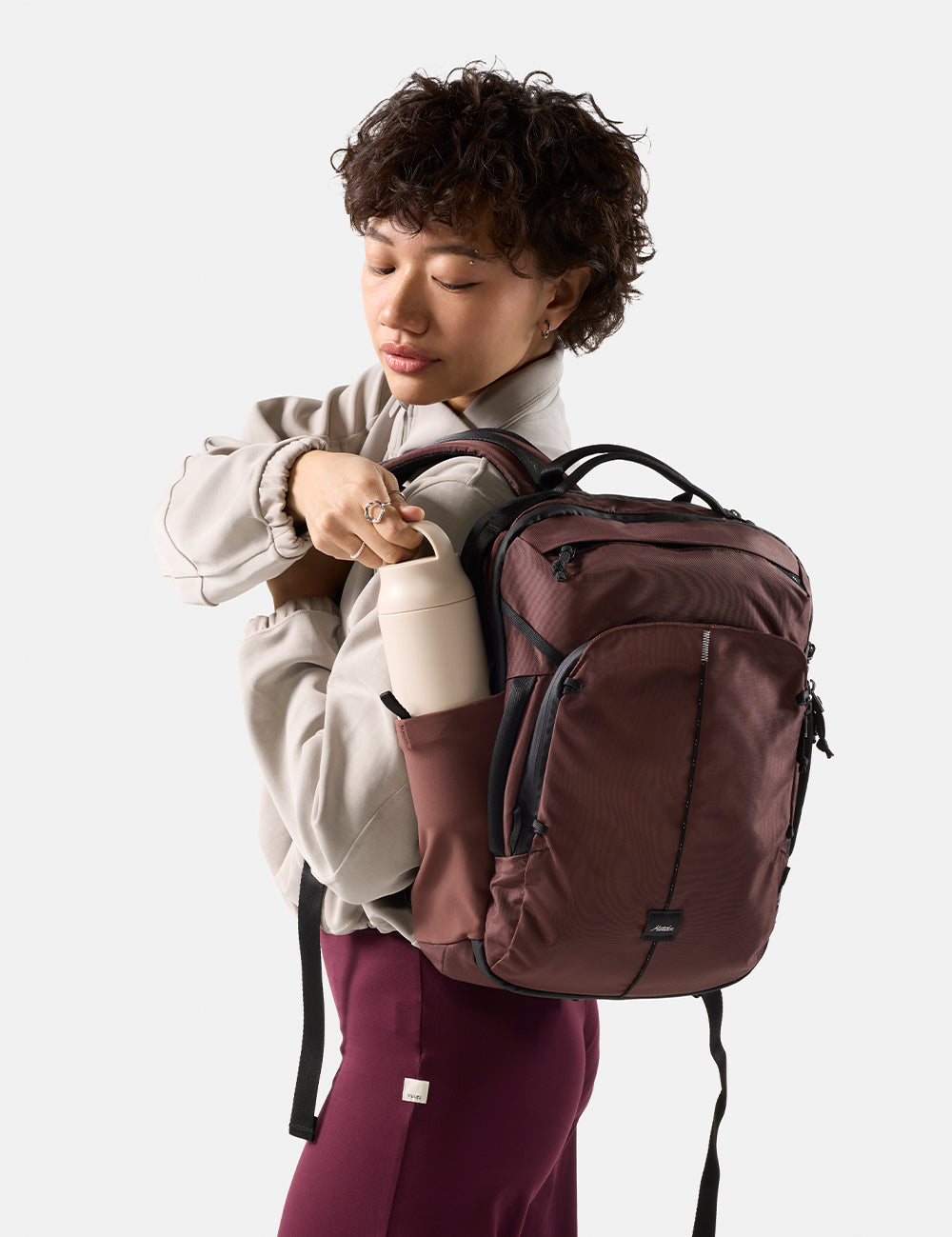 person pulling water bottle out of garnet backpack