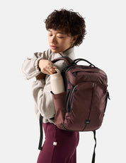 person pulling water bottle out of garnet backpack