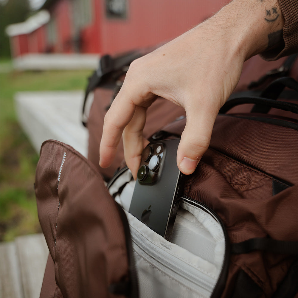 hand taking phone out of garnet backpack