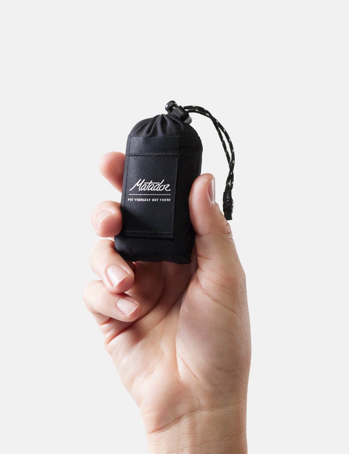 Hand holding a black drawstring bag with a brand logo on a light gray background
