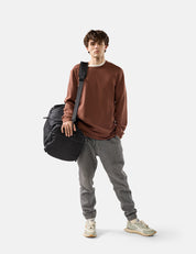 Man holding a black duffel bag against a white background