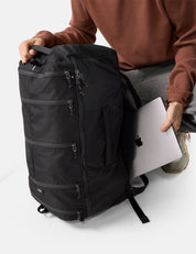 Person holding a black backpack and a laptop on a white background