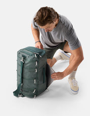 Man unpacking a green backpack on a white background
