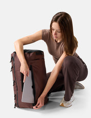 Woman organizing a large Garnet backpack on a white background