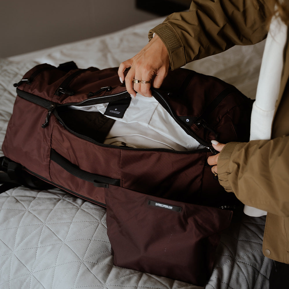 person with garnet duffel on hotel bed