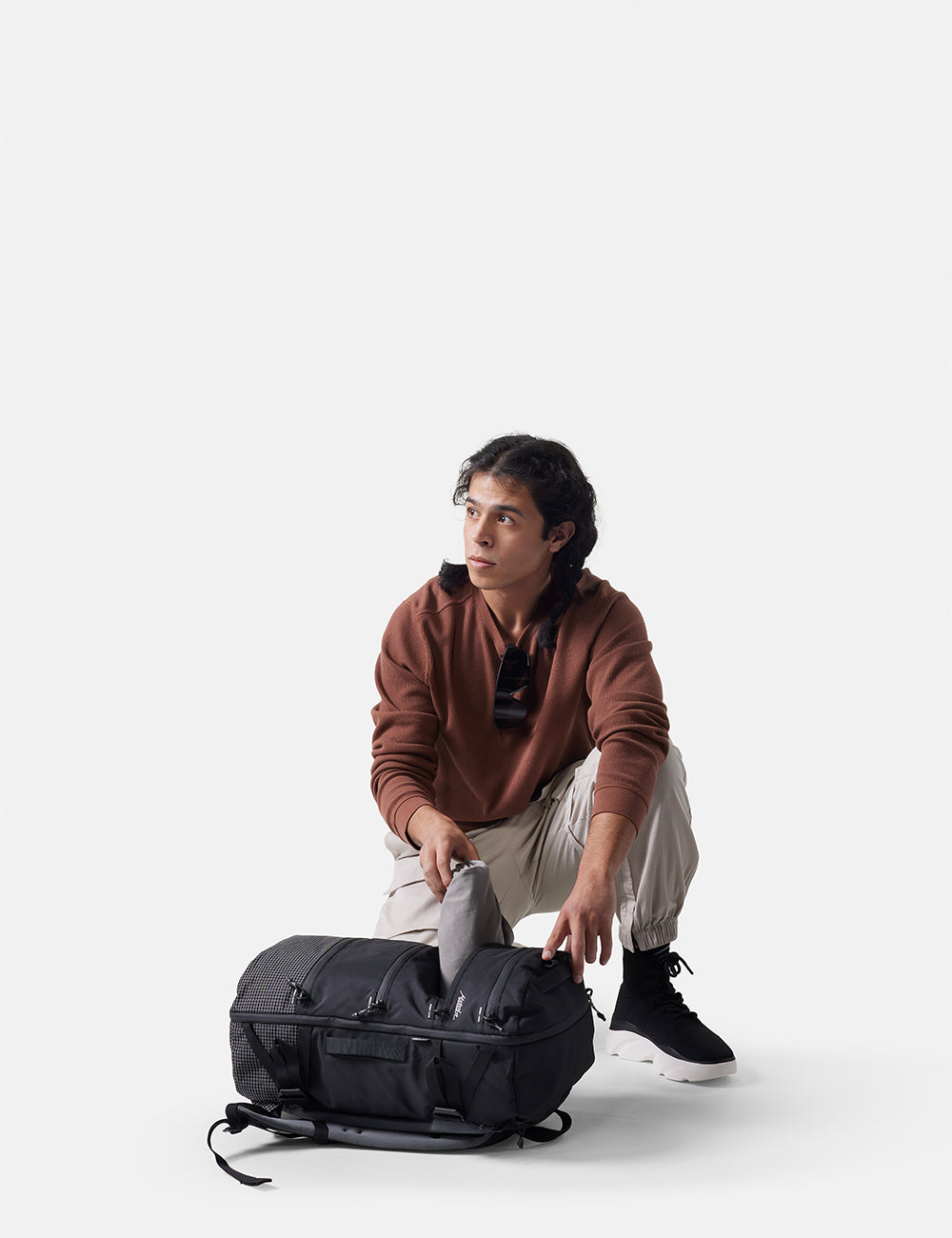 Person opening a black  backpack on a white background