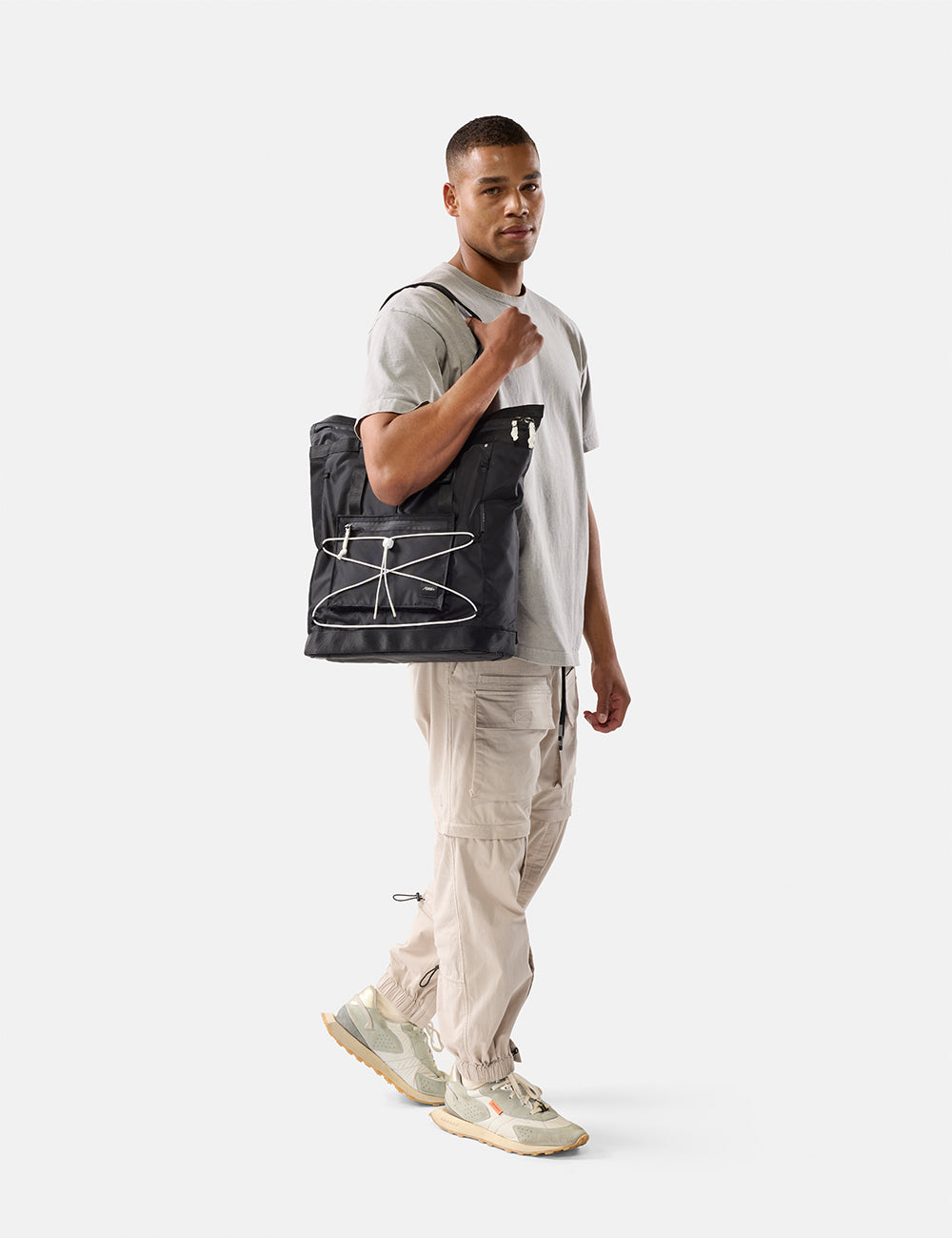 Man holding a black tote bag on a white background