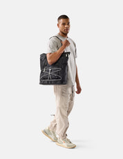 Man holding a black tote bag on a white background