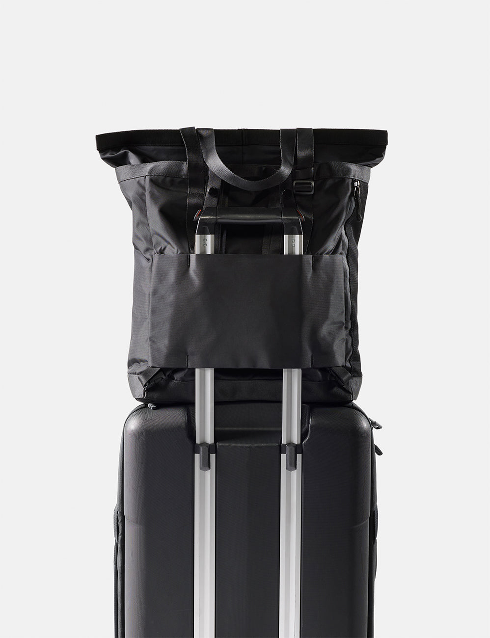 Black tote pack on top of a suitcase with a white background