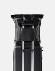 Black tote pack on top of a suitcase with a white background