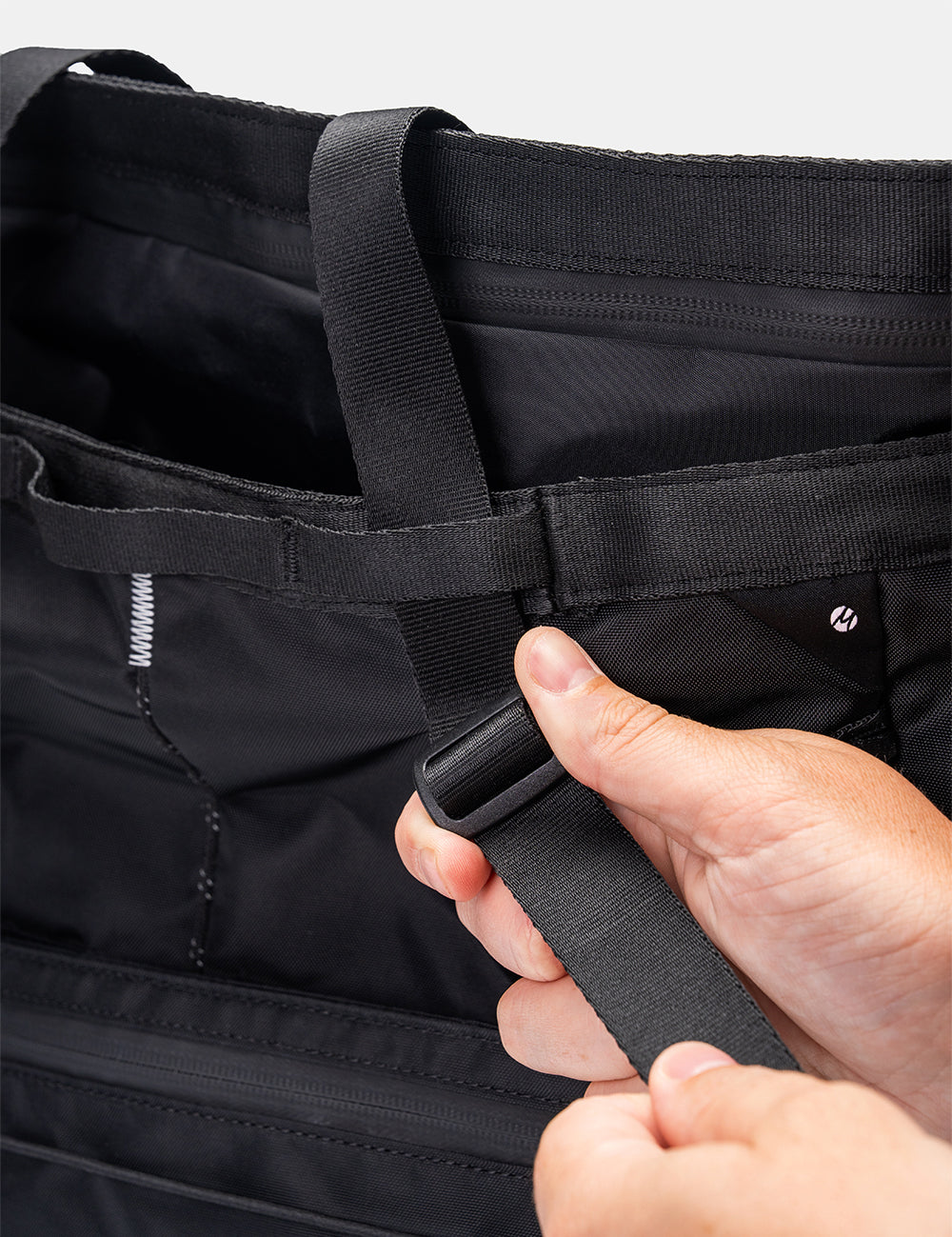 hand adjusting straps of black tote