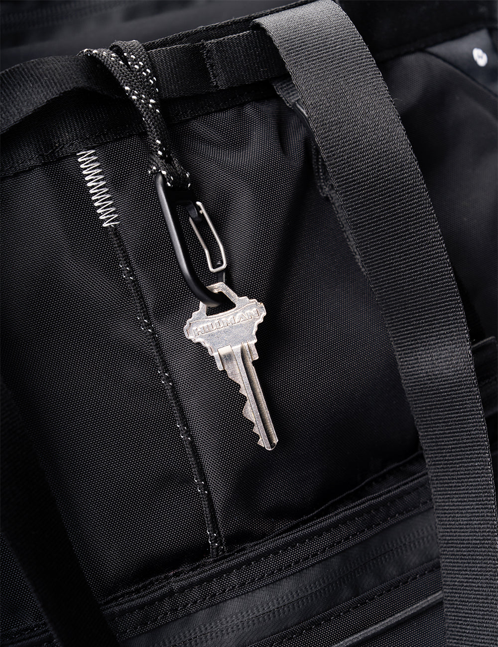 key hanging from carabiner on black bag