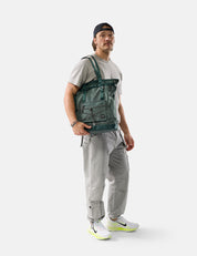 Person wearing a green backpack and gray pants on a white background