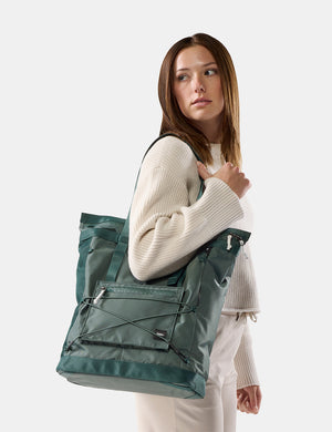 woman on white background wearing green tote over her shoulder