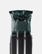 Green tote pack on top of a black suitcase with a white background