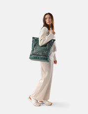 Woman holding a green tote bag against a white background