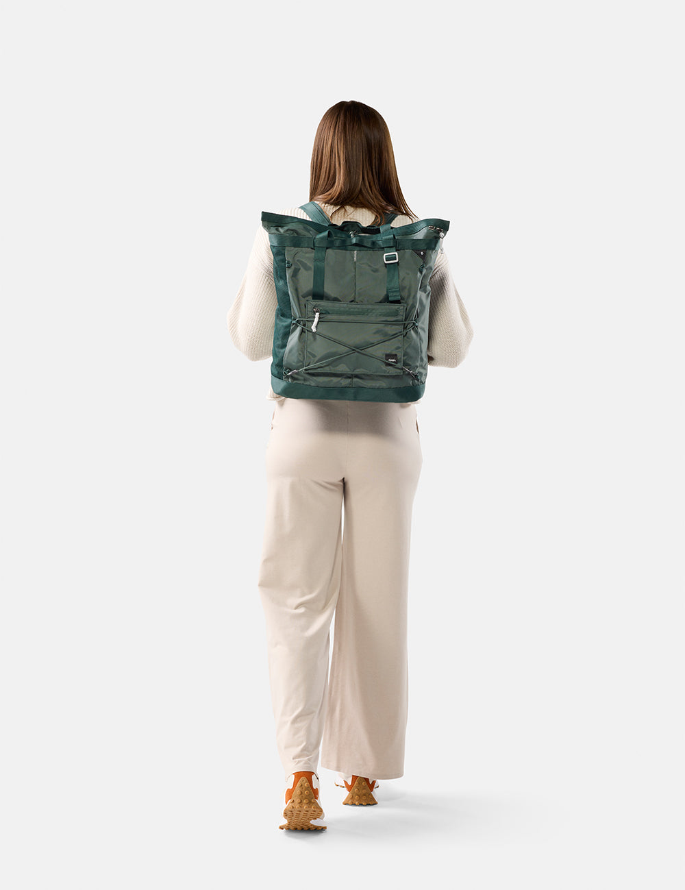 Person wearing a green tote pack on a white background