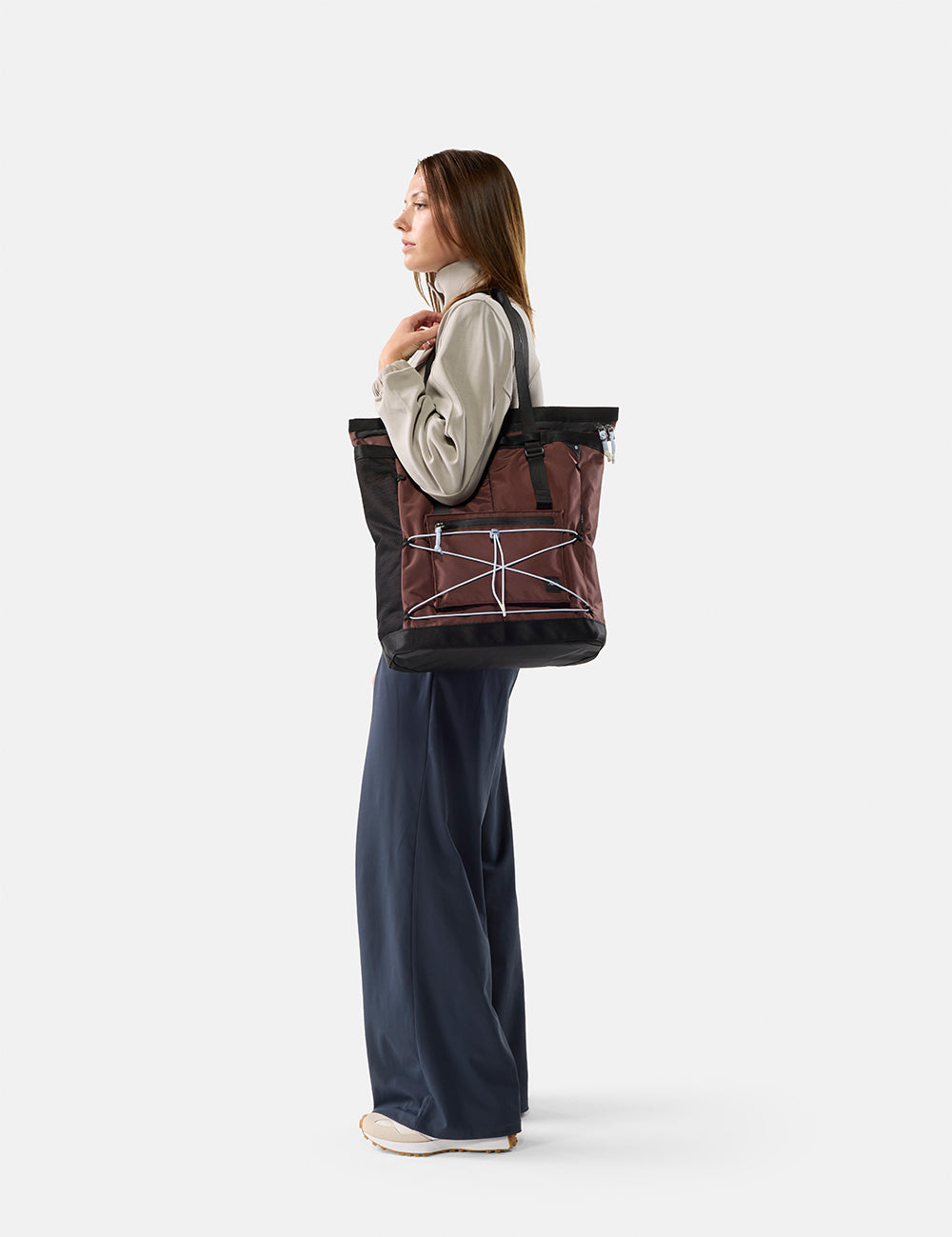 Person holding a large black and garnet tote bag on a white background