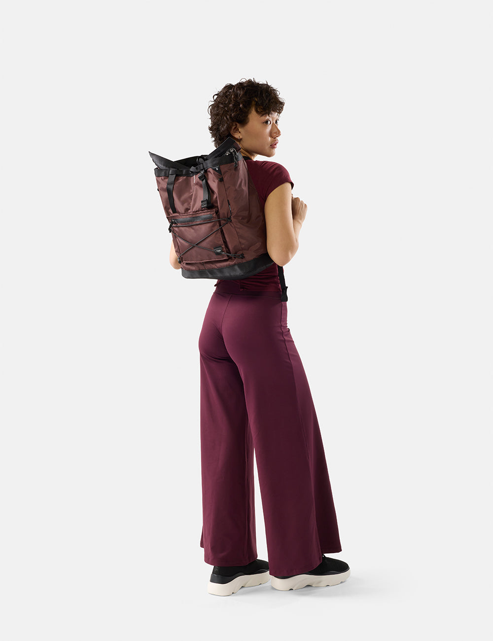 Person wearing a maroon backpack on a white background