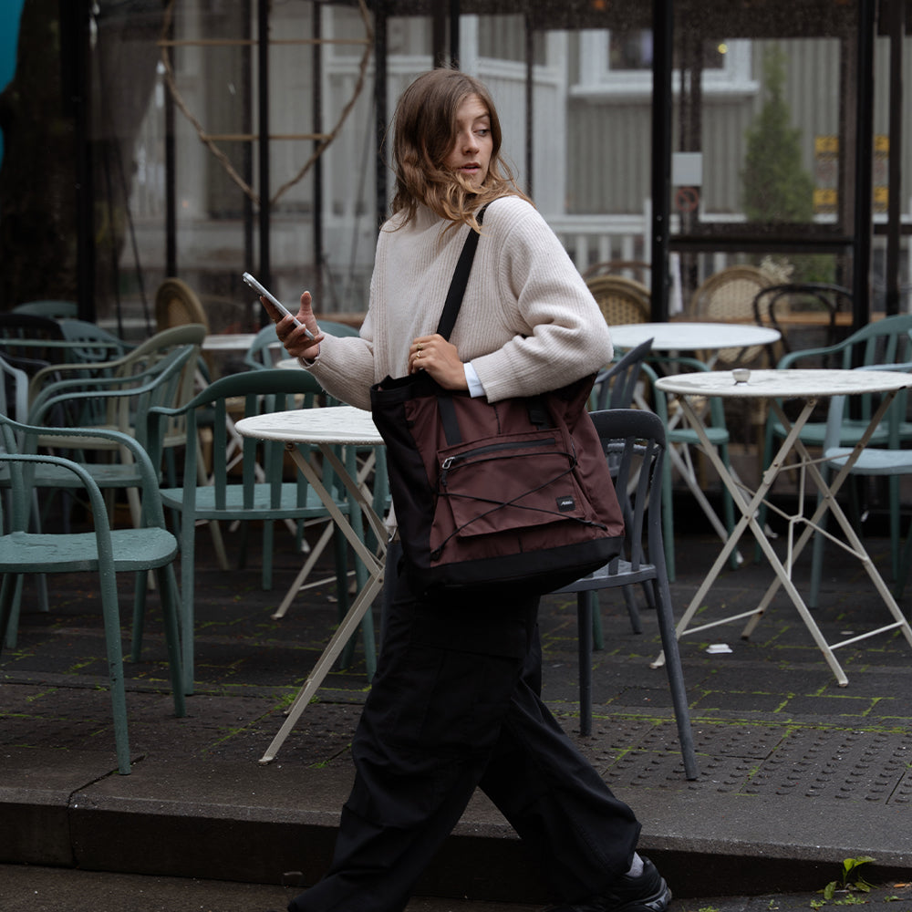 woman walking on moody street with garnet tote