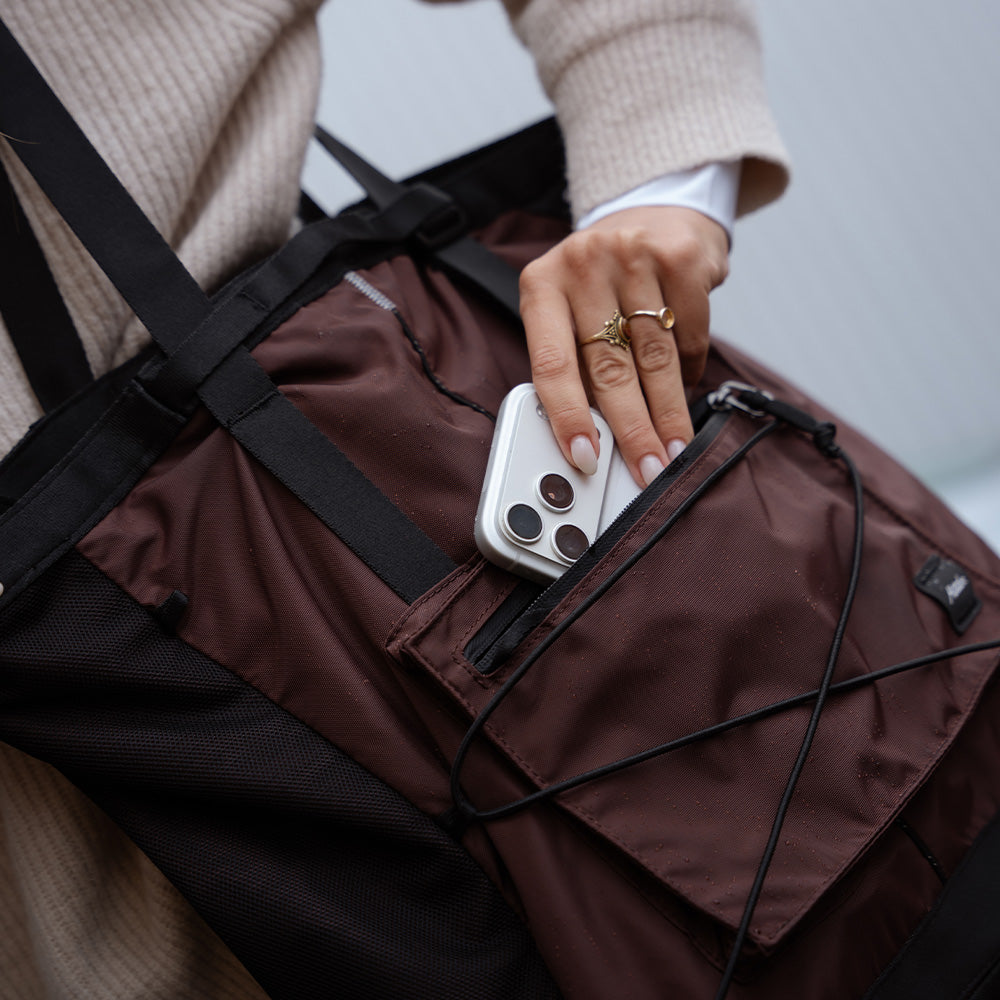 hand pulling phone out of garnet tote
