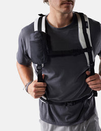 Man wearing a white backpack with straps over his shoulders on a white background