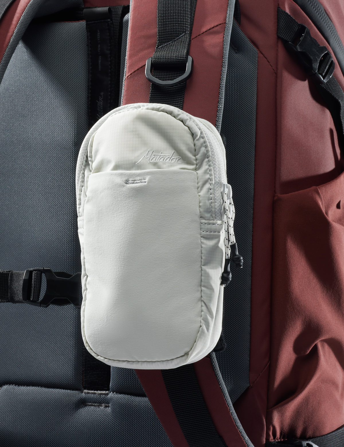 Small white pouch attached to a backpack with visible brand name.