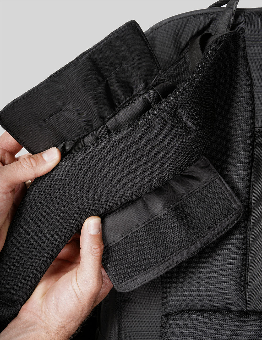 hands installing speed stash onto black backpack strap