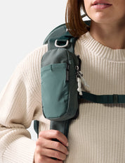 Person wearing a green backpack with a neutral background
