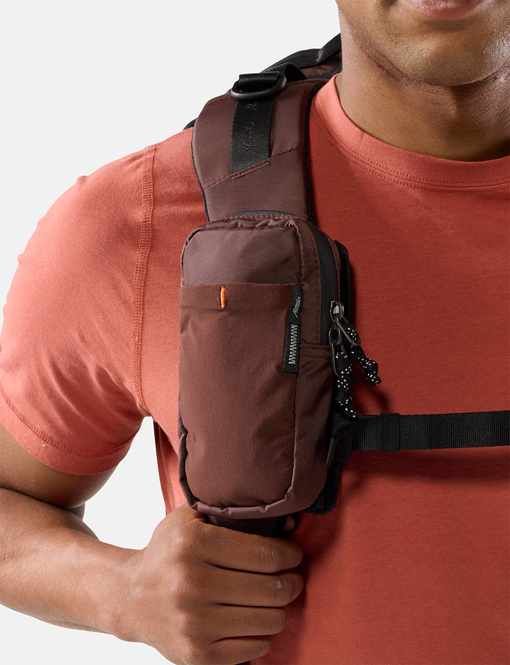 Person wearing a garnet crossbody bag on a plain background