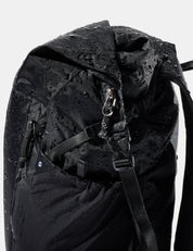 Black backpack with water droplets on a white background