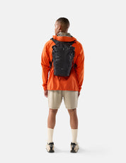 Person wearing an orange jacket and black backpack on a white background