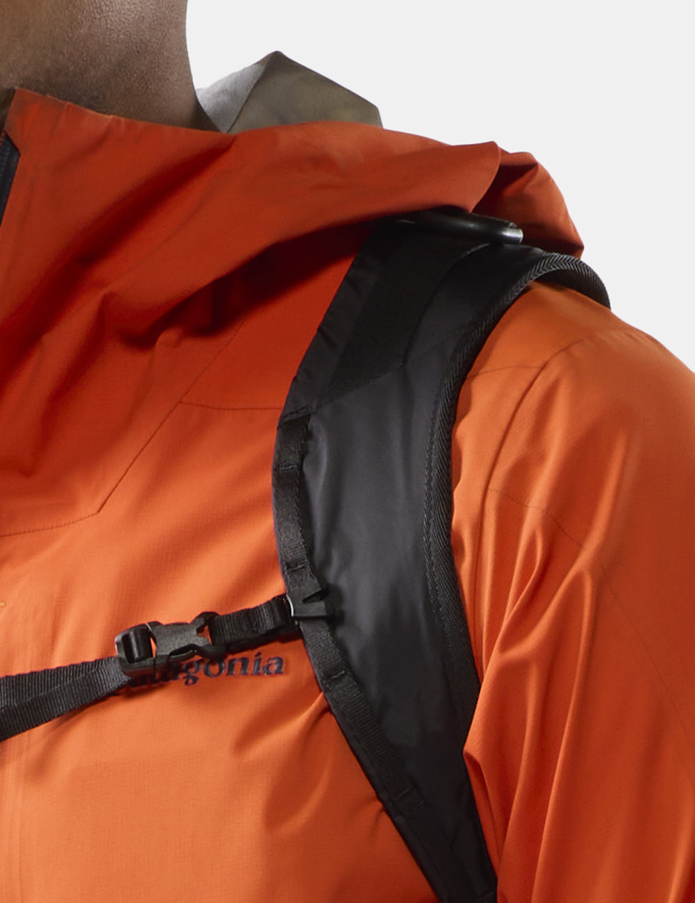 black backpack strap on person in orange jacket