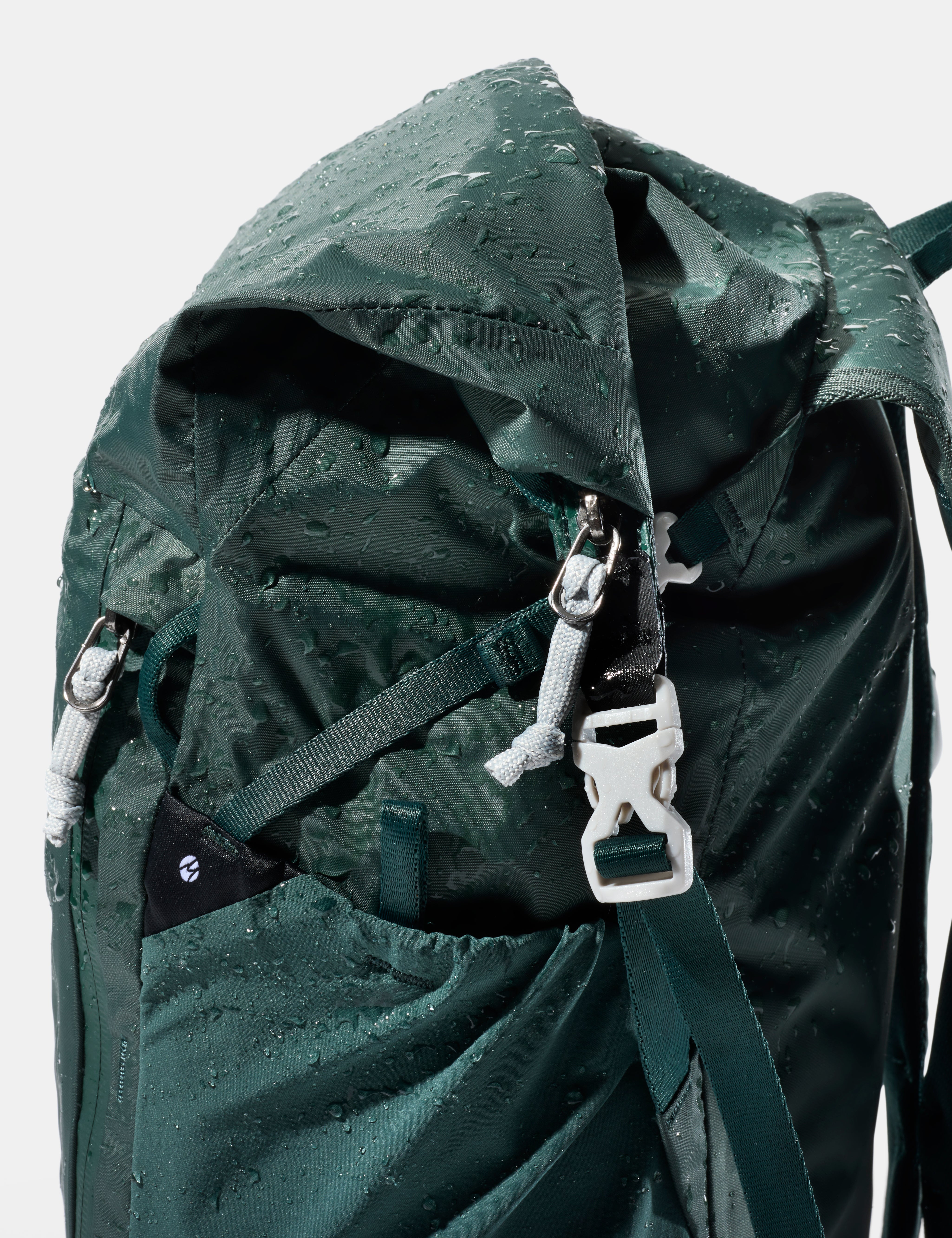 Green backpack with water droplets on a white background