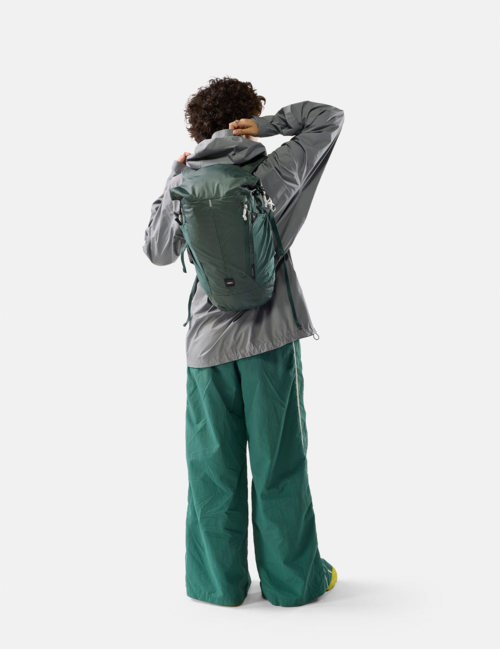 Person wearing a green backpack and green pants on a white background