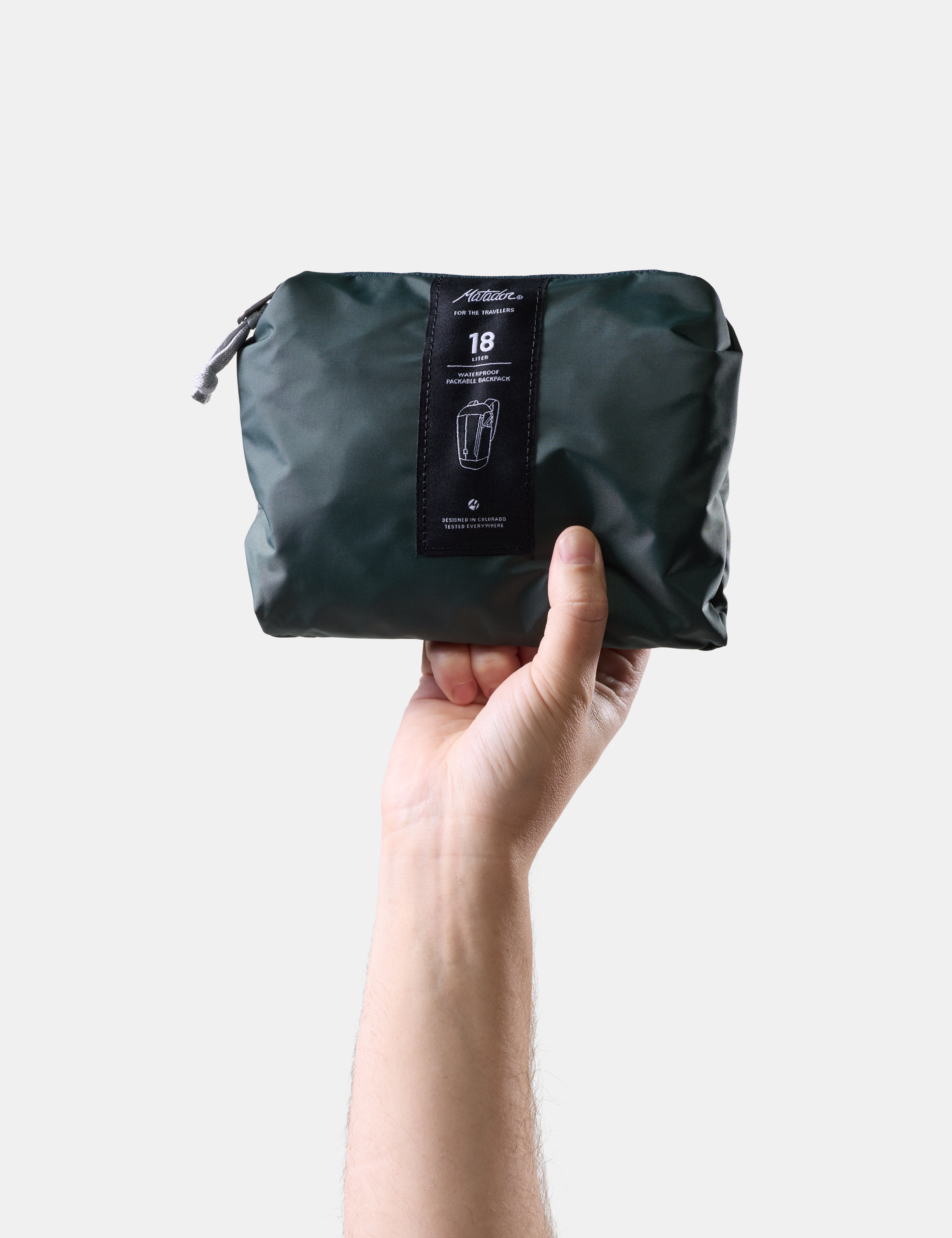 Hand holding a Juniper compression bag with a visible brand label on a light gray background