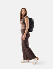 Woman wearing a black backpack and brown pants on a white background