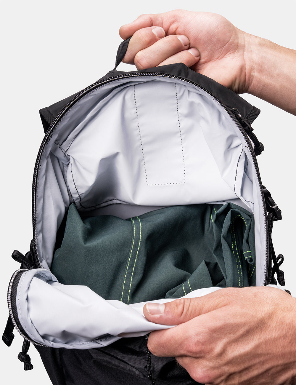 Hands holding backpack open to reveal light colored interior fabric