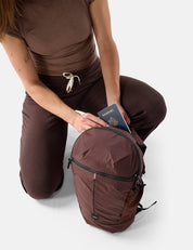 Person in brown outfit with a garnet backpack and passport on a white background
