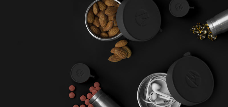 100ml and 40ml canisters on black background holding almonds, headphones and pills