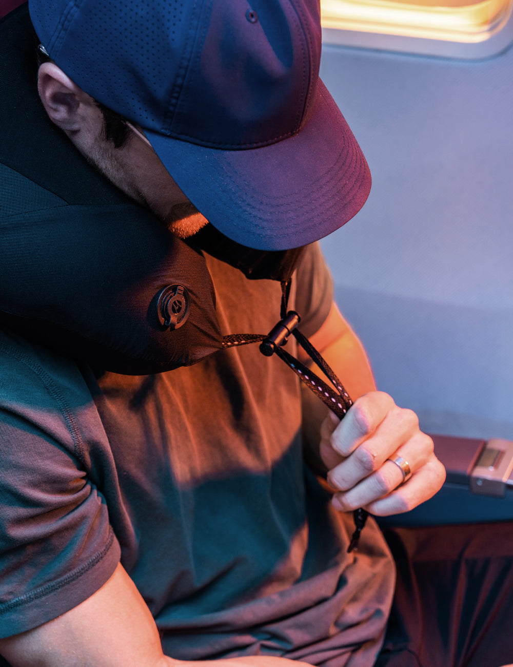 Man on airplane, adjusting neck pillow