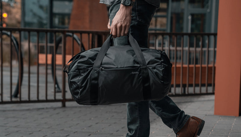 Man in city, carrying On-Grid Duffle by carry handles