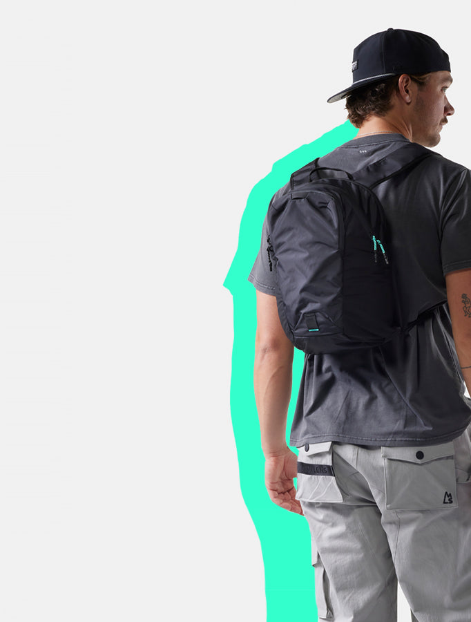 man on white background wearing black backpack with neon teal accents