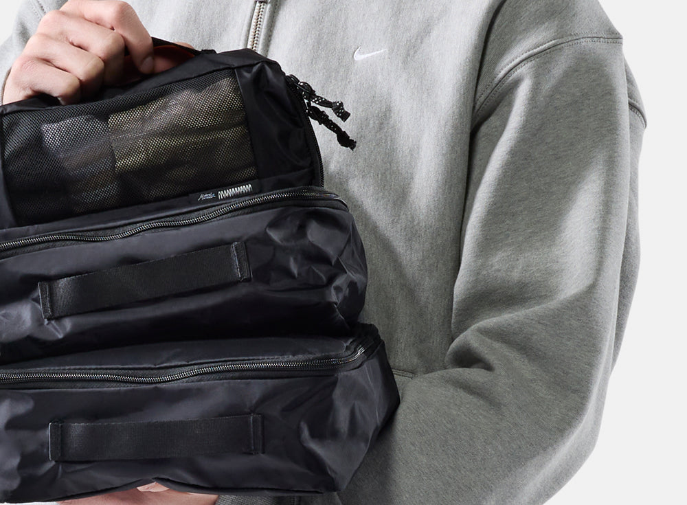 person holding a pile of black packing cubes