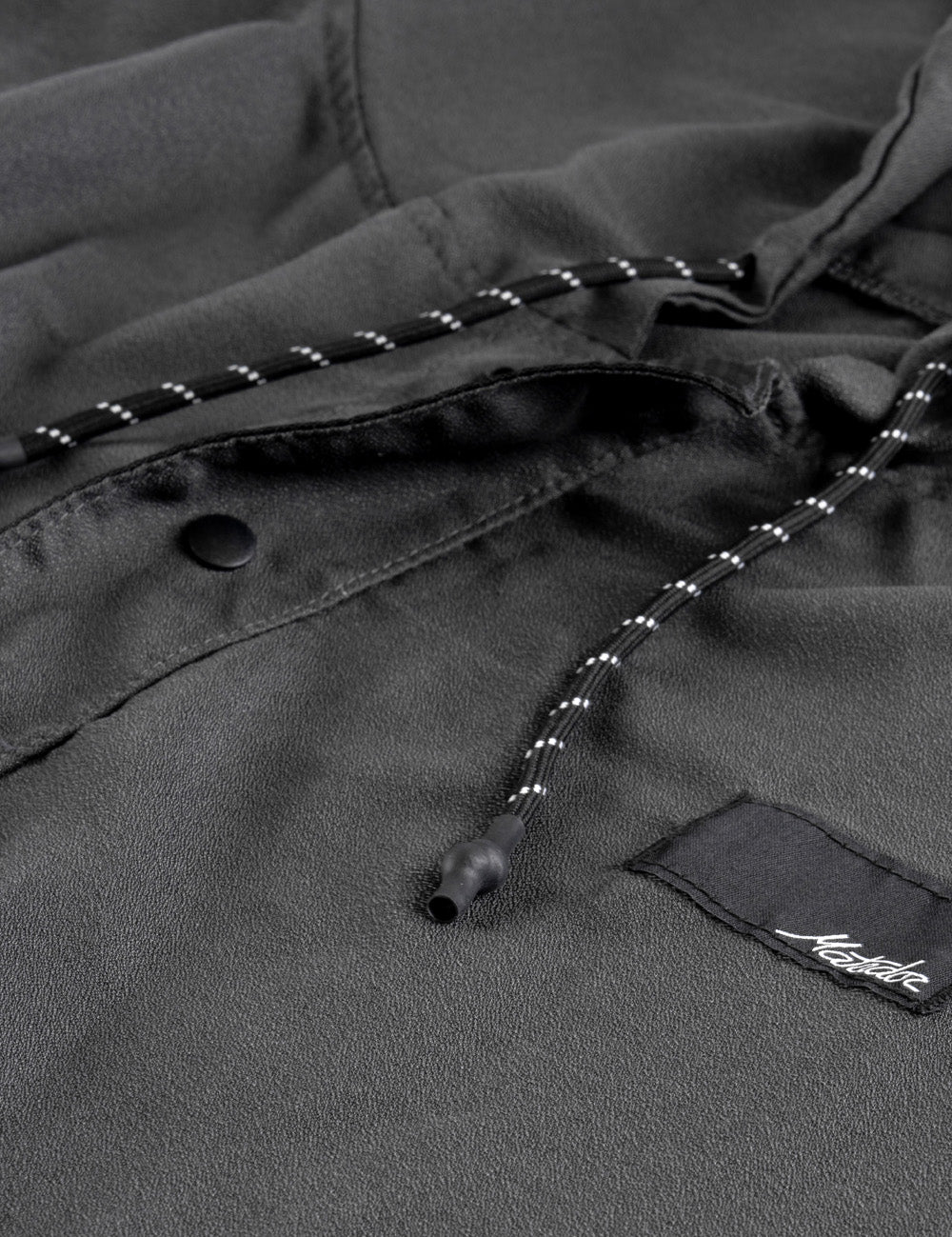 Close-up of a dark gray poncho with a brand logo on a black background