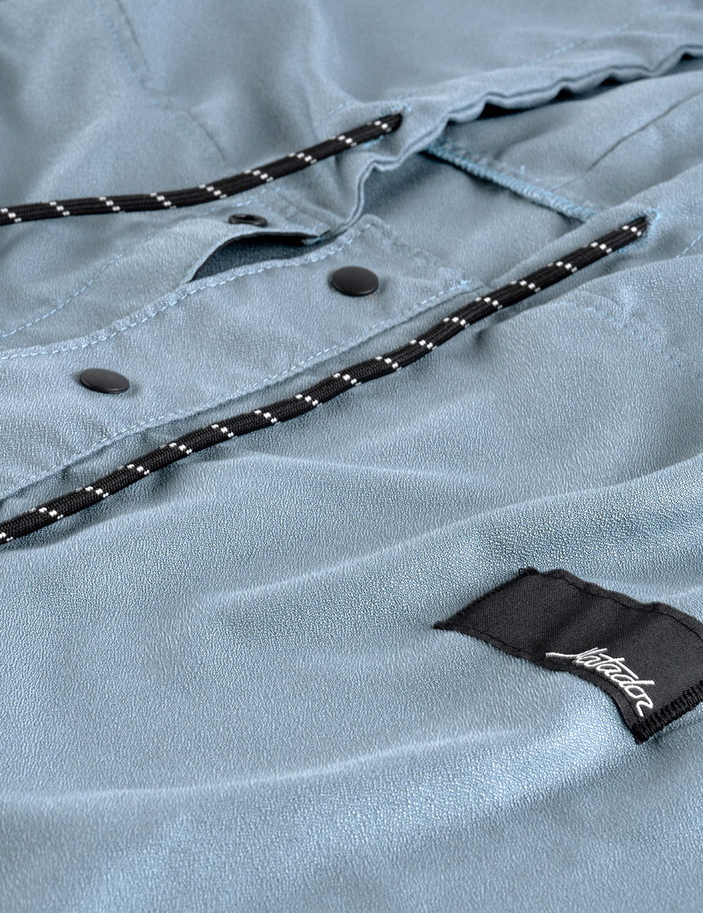 Close-up of a light blue poncho with a brand label on a textured fabric background